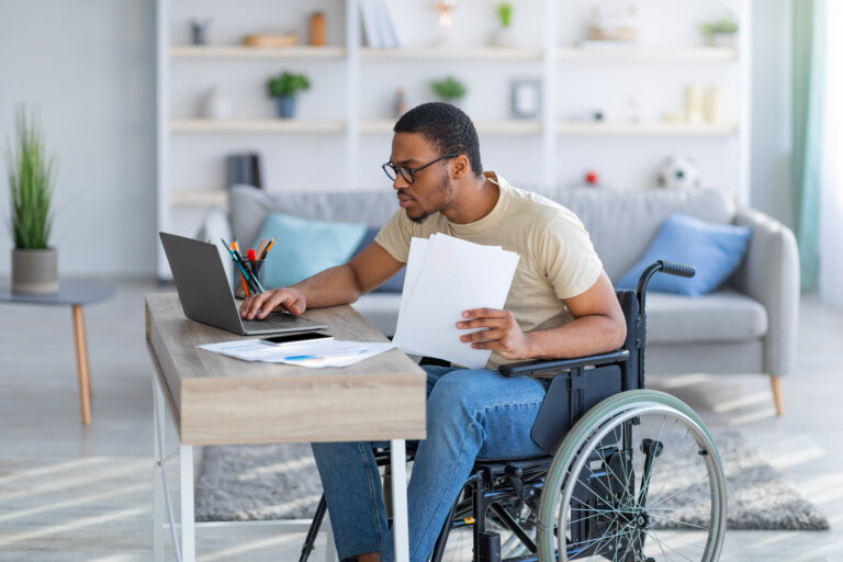 man in a wheelchair holding up a document and on the computer searching what an on-the-record decision is