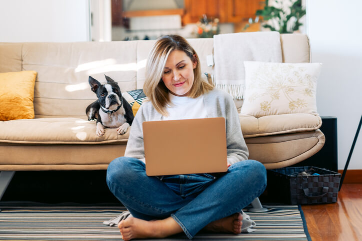 Woman sitting on computer with dog next to her