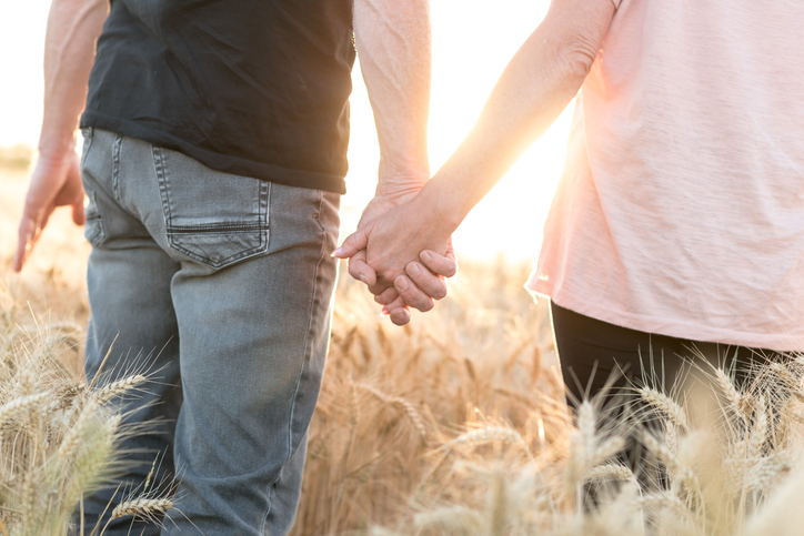 Unmarried couple holding hands together in the sunset