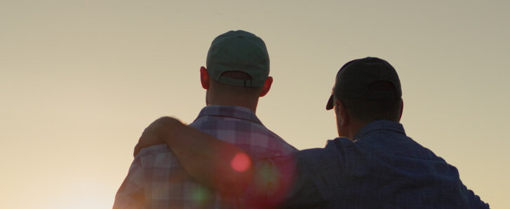 Farmer putting his hand over his son's shoulders