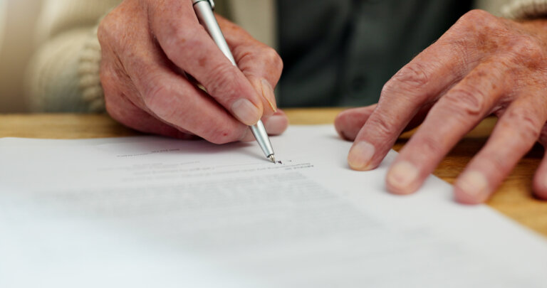 Elderly man signing a piece of paper for charitable planning