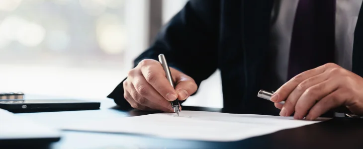 person in a suit writing on a document who is a power of attorney