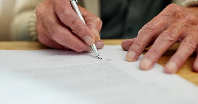 Elderly man signing a piece of paper for charitable planning