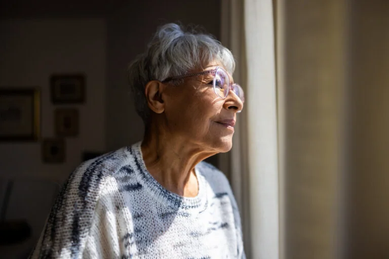 Senior woman looking out the windows of her home